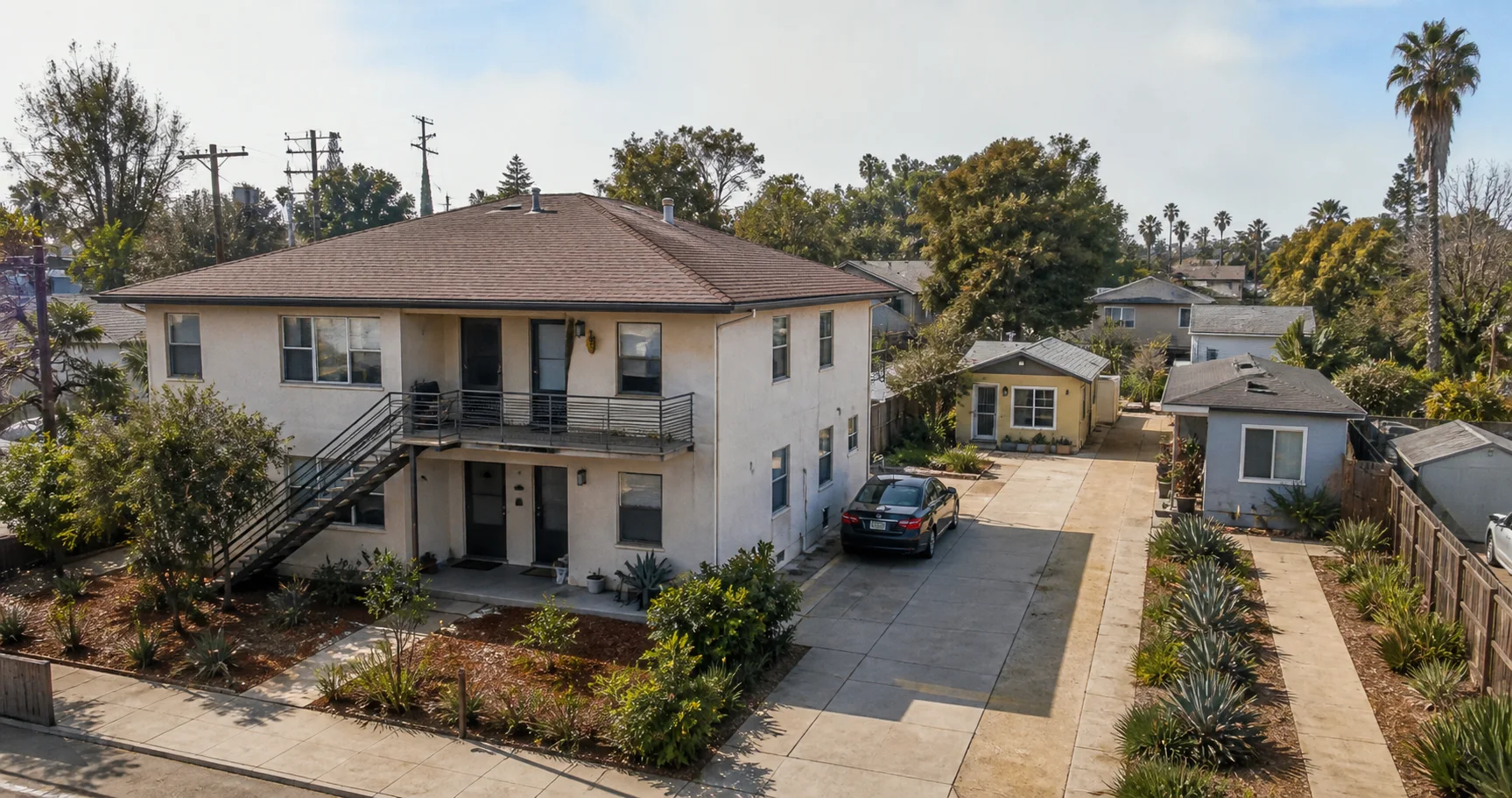 A modest California fourplex with two small detached cottages behind it