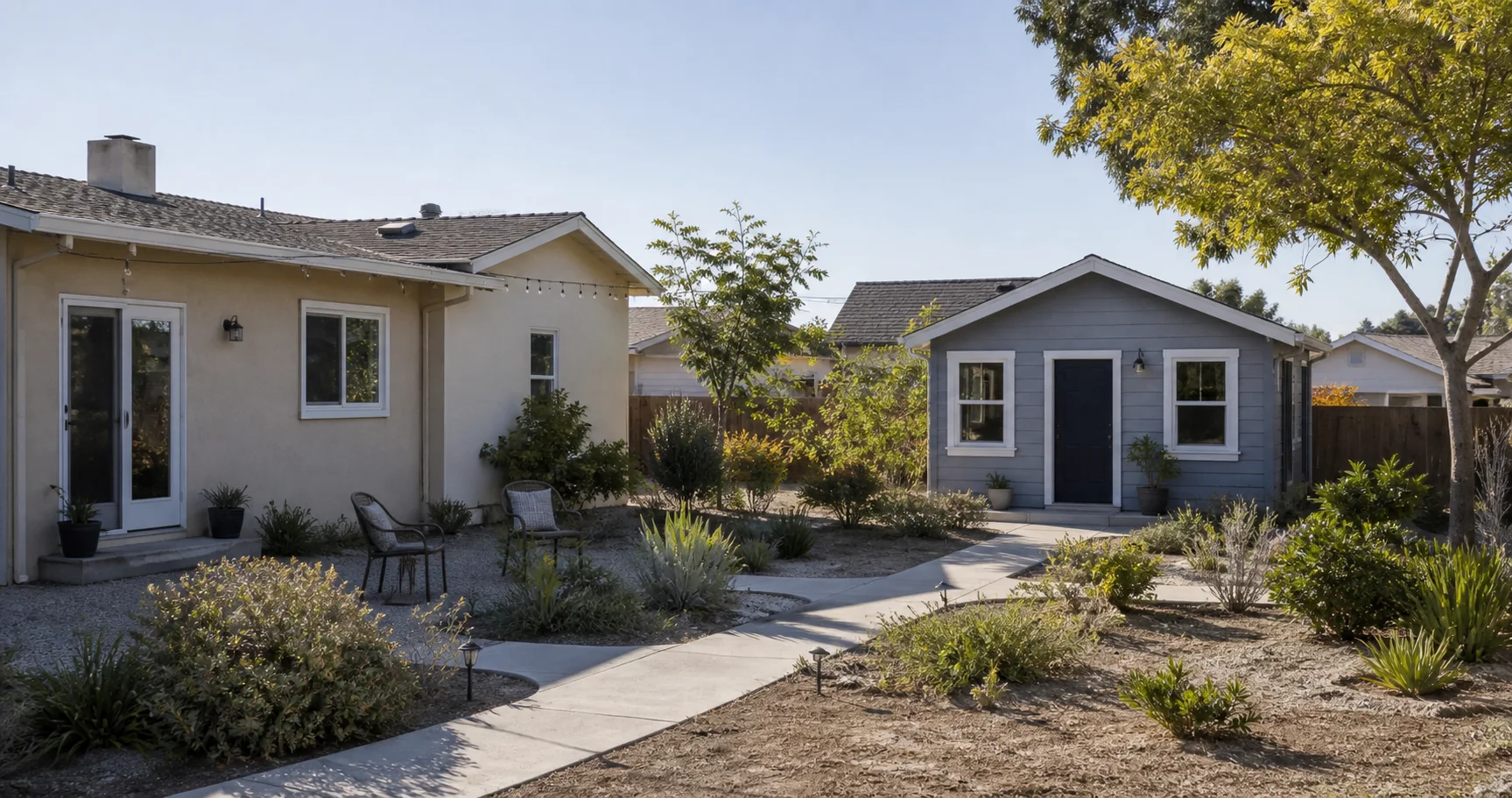 A modest California house and detached backyard cottage connected by a garden path